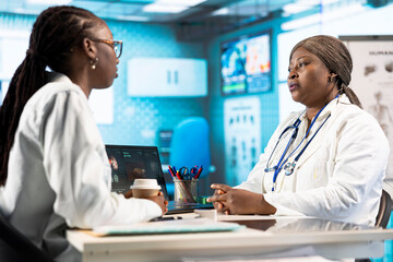 Black general practitioner explaining clinical records and results to a patient during a health...