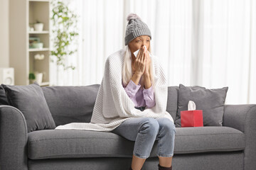Obraz premium Woman wrapped in blanket sitting on a sofa