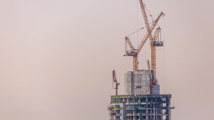 Under construction high-rise building with yellow construction crane in Dubai timelapse