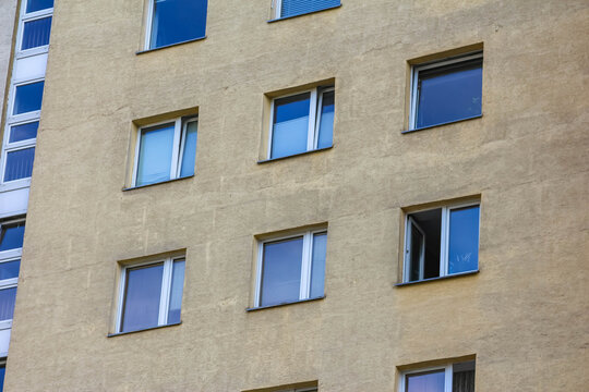 Multi-story residential apartment building with blue accents and balconies against clear sky - Powered by Adobe