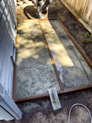 Concrete poured into pad and frame with contraction worker putting in rebar plus various tools on the ground