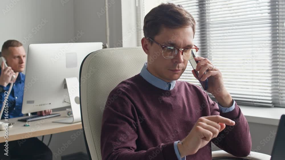 Wall mural medium shot of focused male manager typing on smartphone screen then starting talking on phone call 