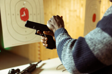 Indoor shooting range client cocking firearm, setting mechanism up for firing bullets. Close up...