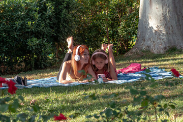 Mother and daughter enjoying music and smartphone in park