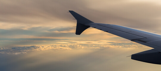 Wing of a plane in a beautiful cloudy sky in the evening light.