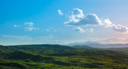 Rolling green hills under dramatic cloudy sky. Landscape capturing rolling green hills stretching...