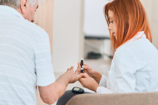 Young Female doctor or nrse checking patient's blood sugar level using digital glucose meter for check sample blood sugar level to treat diabetes.