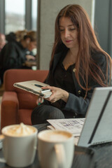 A woman is comfortably sitting at a table where there are two cups of steaming coffee placed and in...