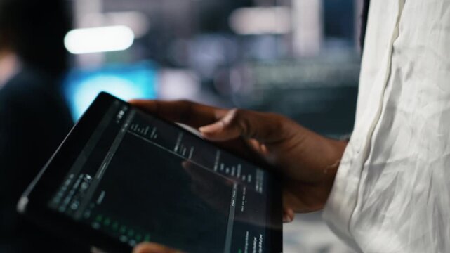 Close up of data center software developer using tablet to review code for automation scripts. Server hub IT specialist using device, monitoring error logs for debugging processes, camera A