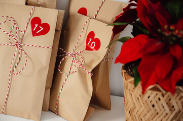 handmade Advent christmas calendar bags near poinsettia.winter holidays concept