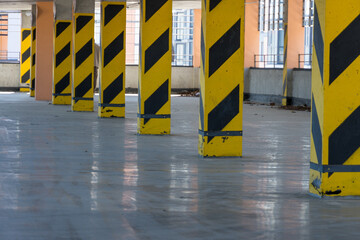 Support columns designed with yellow and black stripes stand tall in a spacious parking area. The...