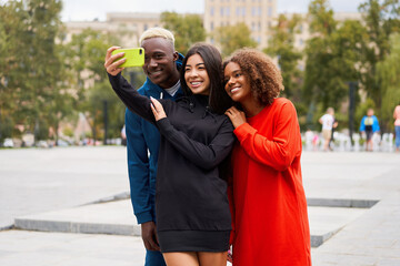 Multi ethnic friends outdoor taking a selfie on smartphone. Diverse group people Afro american asian spending time together Multiracial male female student meeting outdoors