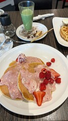 Delicious Pancakes with Fresh Berries and Cream, Matcha Latte with Waffles on Wooden Table