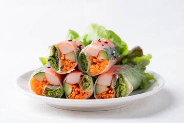 Salad roll with crab stick, carrot, cucumber and lettuce wrapped with rice paper on dish