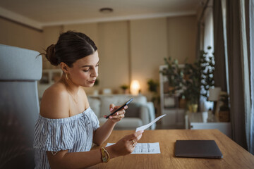 Adult woman have contactless payment scan invoice on cellphone at home