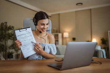 adult woman with headset hold and show clipboard during video call