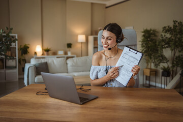 adult woman with headset hold and show clipboard during video call