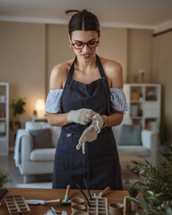woman gardener put gloves on hands, take care grow cultivate plants