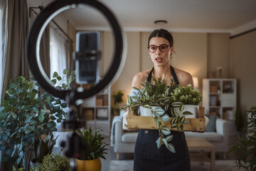 woman gardener blogger show her potted plants recording video at home