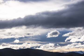 contrasty sky with dark and white clouds over tasmanian mountains in Australia