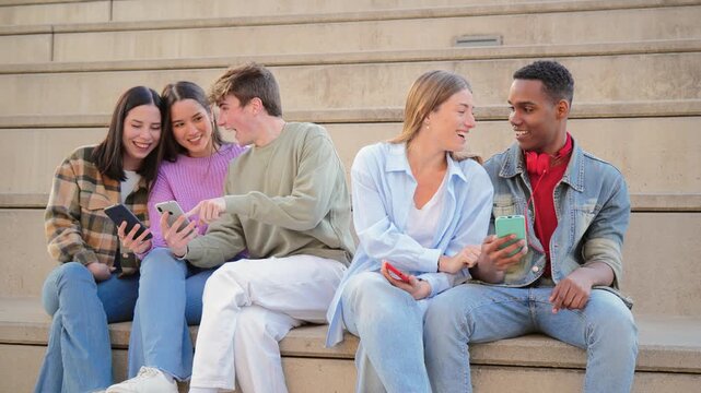 A lively group of friends joyfully interacting with their smartphones, sharing moments and experiences while seated together on steps. Their excitement and connection shine through their activities.