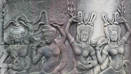 Angkor Wat, Cambodia - 3 July 2025. Intricately carved female figures in motion, adorned with detailed hair and attire, appear on an ancient sandstone temple wall.