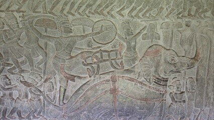 Angkor Wat, Cambodia - 3 July 2025. Elephant-led warriors with raised arms and shields move in action across a detailed temple wall carving.