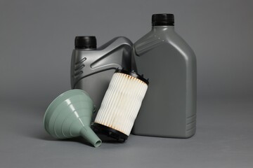 Motor oil in plastic canisters, filter and funnel on grey background