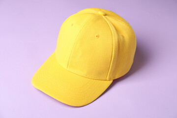 Yellow baseball hat on violet background, closeup. Mockup for design