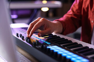 Man working with MIDI keyboard at table indoors, closeup