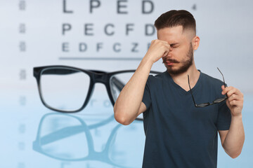 Man with eyesight problems, glasses and vision test chart