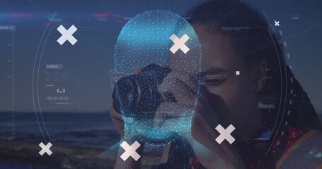 Female photographer in polka dot top holding compact camera at rocky shore, with scanning overlay