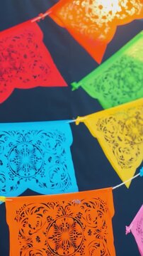 Colorful papel picado flags hanging on string against dark background. Studio shot. Day of the Dead and Mexican holiday celebration. Festive decoration concept. Design for banner, poster, greeting