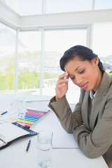 African American woman in suit sitting at office desk examining bar chart and notebook, copy space