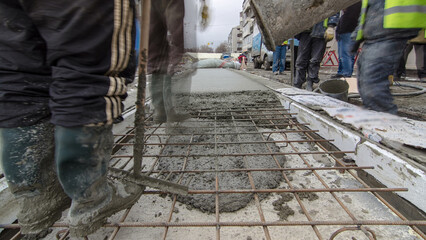 Pouring ready-mixed concrete after placing steel reinforcement to make the road by concrete mixer...