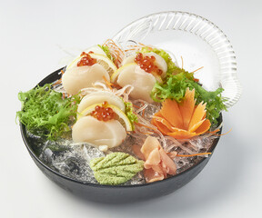 Freshly prepared sashimi platter featuring scallops, salmon roe, shredded radish, and garnished...