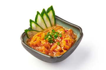 Bowl of vibrant jellyfish salad garnished with sesame seeds, green onions, and sliced cucumbers, served ceramic dish. dish showcases mix of textures and flavors, offering refreshing and savory