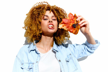 Young woman enjoying pizza with an expression of delight, showcasing her curly hair and casual...