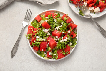 Plates of tasty watermelon salad on light background