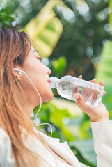 Vertical Young Woman Drinking Water bottle outdoor park traveler. Asian female drinking water...