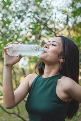 Vertical Young Woman Drinking Water bottle outdoor park traveler. Asian female drinking water...