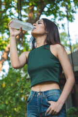 Vertical Young Woman Drinking Water bottle outdoor park traveler. Asian female drinking water...