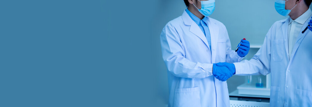 Banner Two asian scientist men team partner shake hands together. Men researcher holding chemistry science tube experiment biotech antibody in laboratory. Coworker scientist partner with copy space