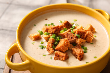 Pot of tasty cream soup with croutons on grey tile background