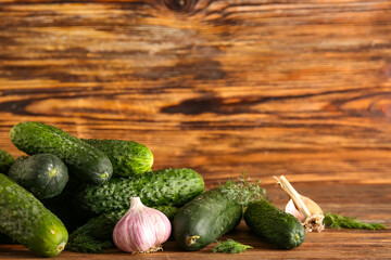 Heap of fresh cucumbers with garlic and dill on wooden background