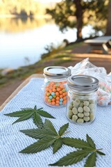 An outdoor setting featuring jars of colorful edible candies and green plant leaves, set against a serene lake view, capturing a relaxed and vibrant atmosphere.
