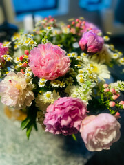 Romantic bouquet of peonies and daisies on kitchen table