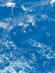 Blue ocean waves with white sea foam in sunlight
