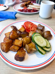 Plate of roasted potatoes with fresh cucumber and tomato