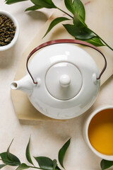 Teapot with cup, bowl of dry tea and leaves on white grunge background